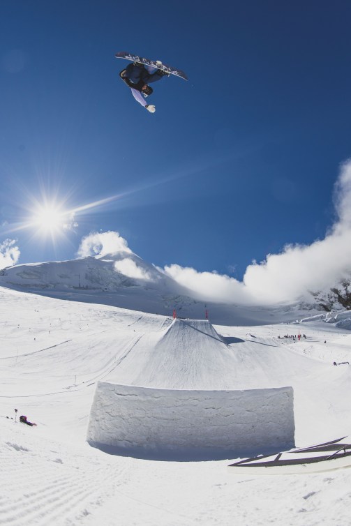 Snowboard flies in the blue sky above a snow jump 