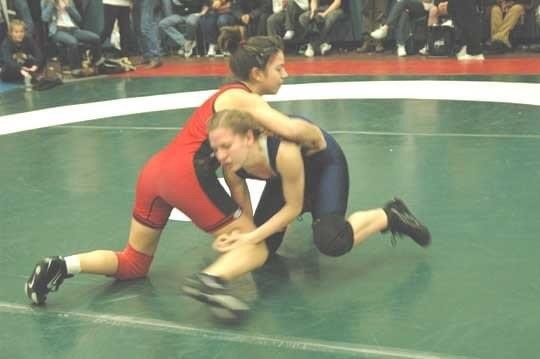 Two youth wrestlers grapple on a green mat