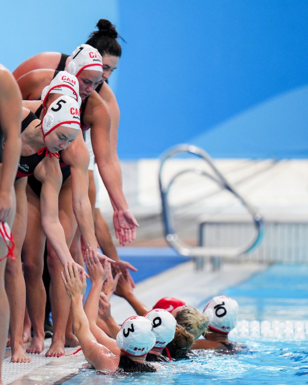 Team Canada women's water polo players high five each other