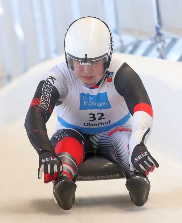 Luge athlete sits up on their sled.