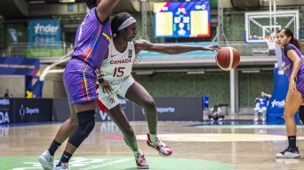 A basketball player reaches her arm out to full extension to hold onto the ball