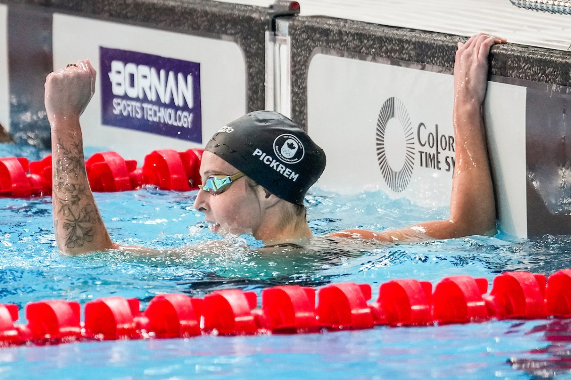 Sydney Pickrem pumps her fist while hanging off the pool wall 