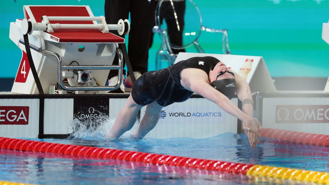 Ingrid Wilm dives backwards into the water to start a backstroke race