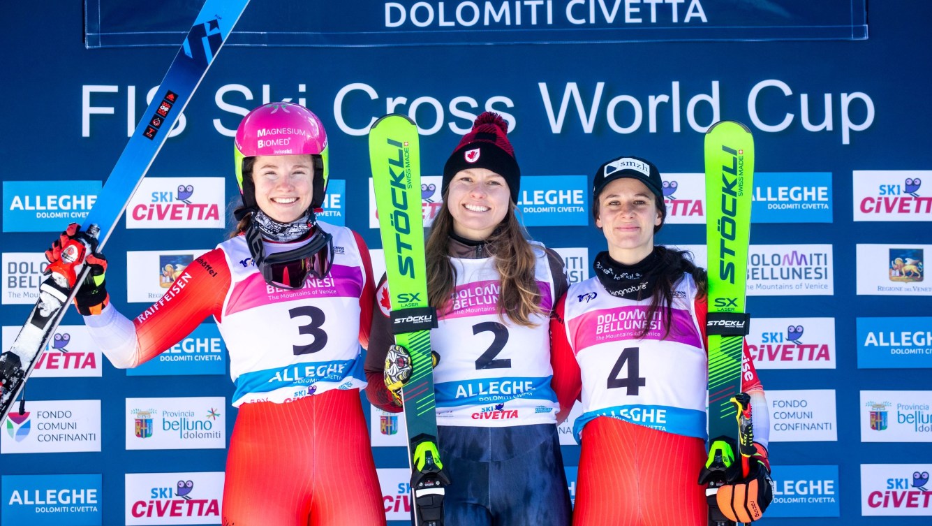 Three women ski cross racers stand on a podium