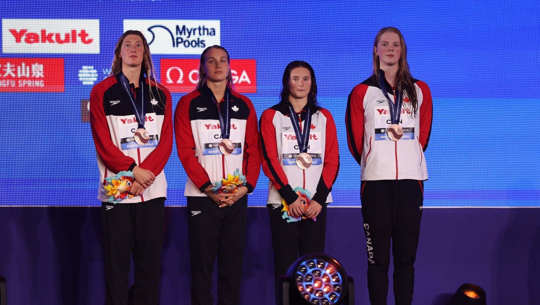 Fourn Team Canada swimmers stand on a podium