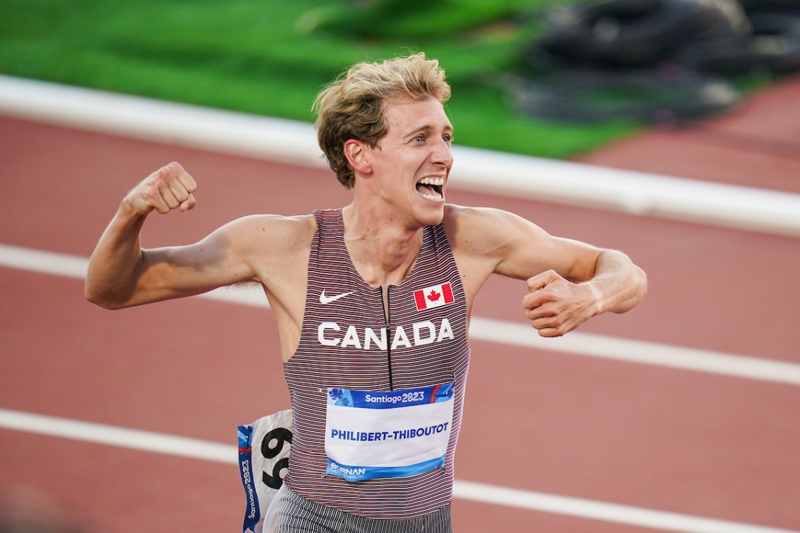 Charles Philibert-Thiboutot pumps his fist at the finish line of the men's 1500m at the Santiago Pan Am Games while wearing a red, black and white team Canada speed suit.