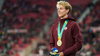 Charles Philibert-Thiboutot stands proudly on the podium at the Santiago 2023 Pan Am Games with his gold medal. He is wearing a maroon Team Canada jacket.