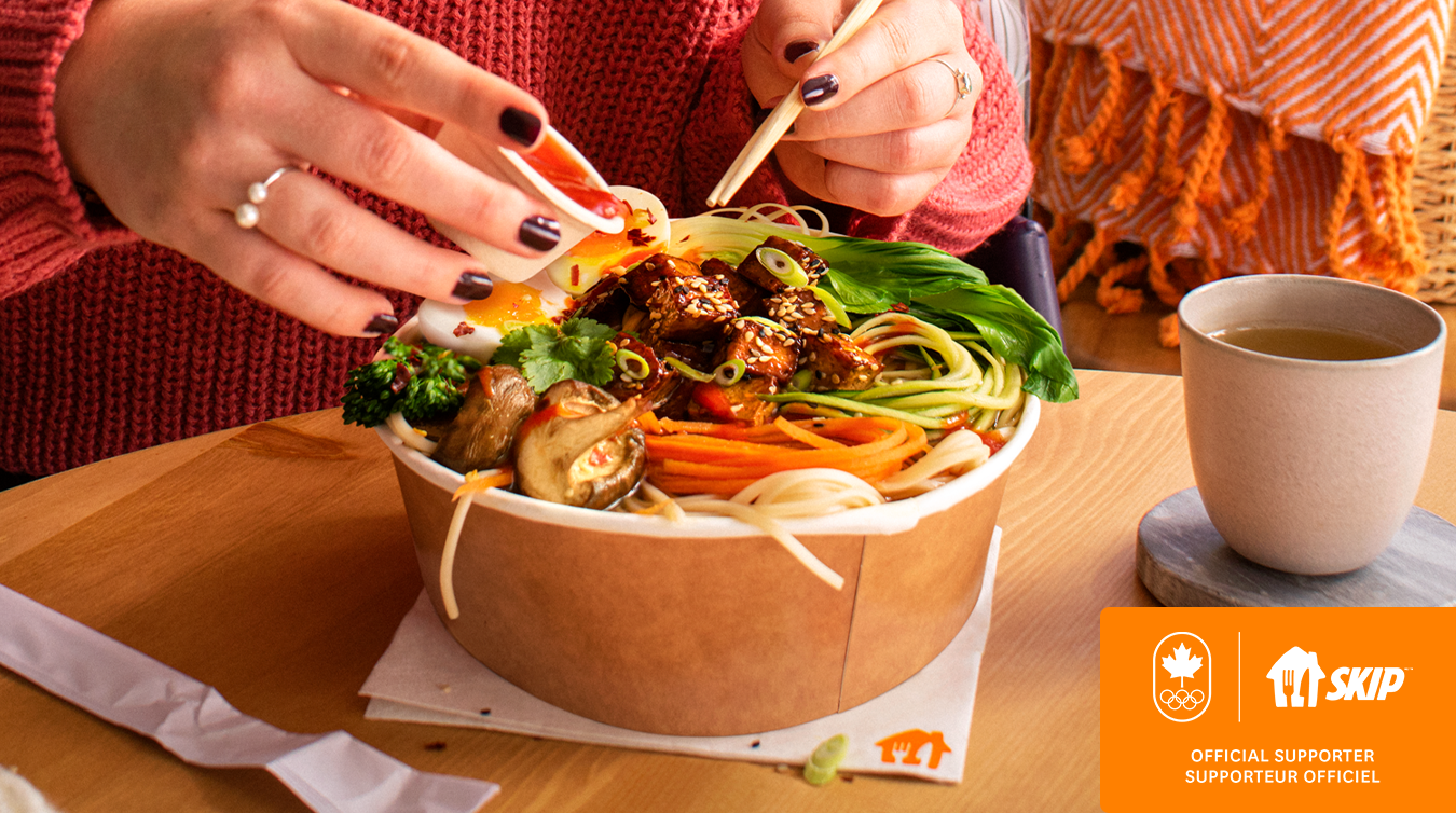 hands holding chopsticks over a bowl of food