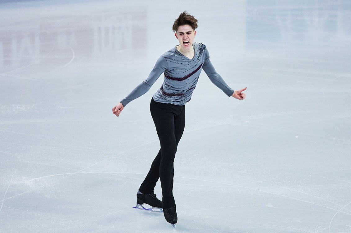 Roman Sadovksy in a grey shirt and black pants performs a figure skating routine