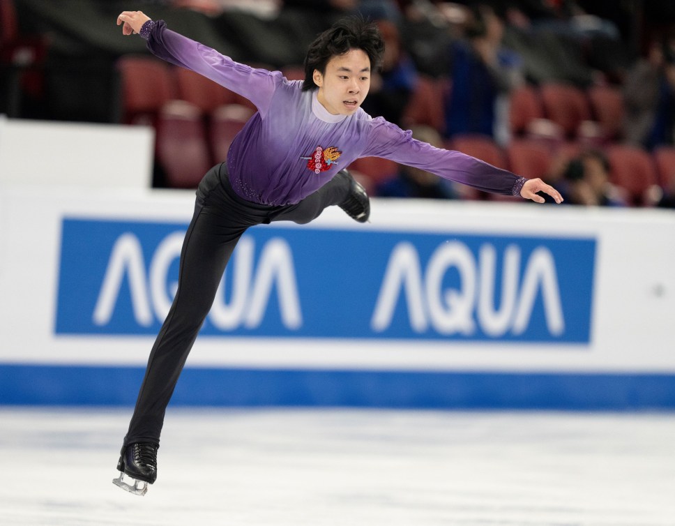 Wesley Chiu in a purple shirt and black pants competes in figure skating 