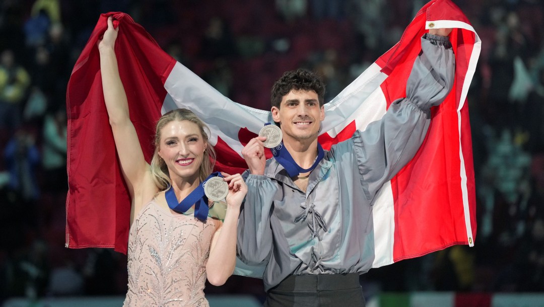 Piper Gilles and Paul Poirier pose with their silver medals and a Canadian flag