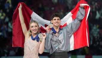 Piper Gilles and Paul Poirier pose with their silver medals and a Canadian flag