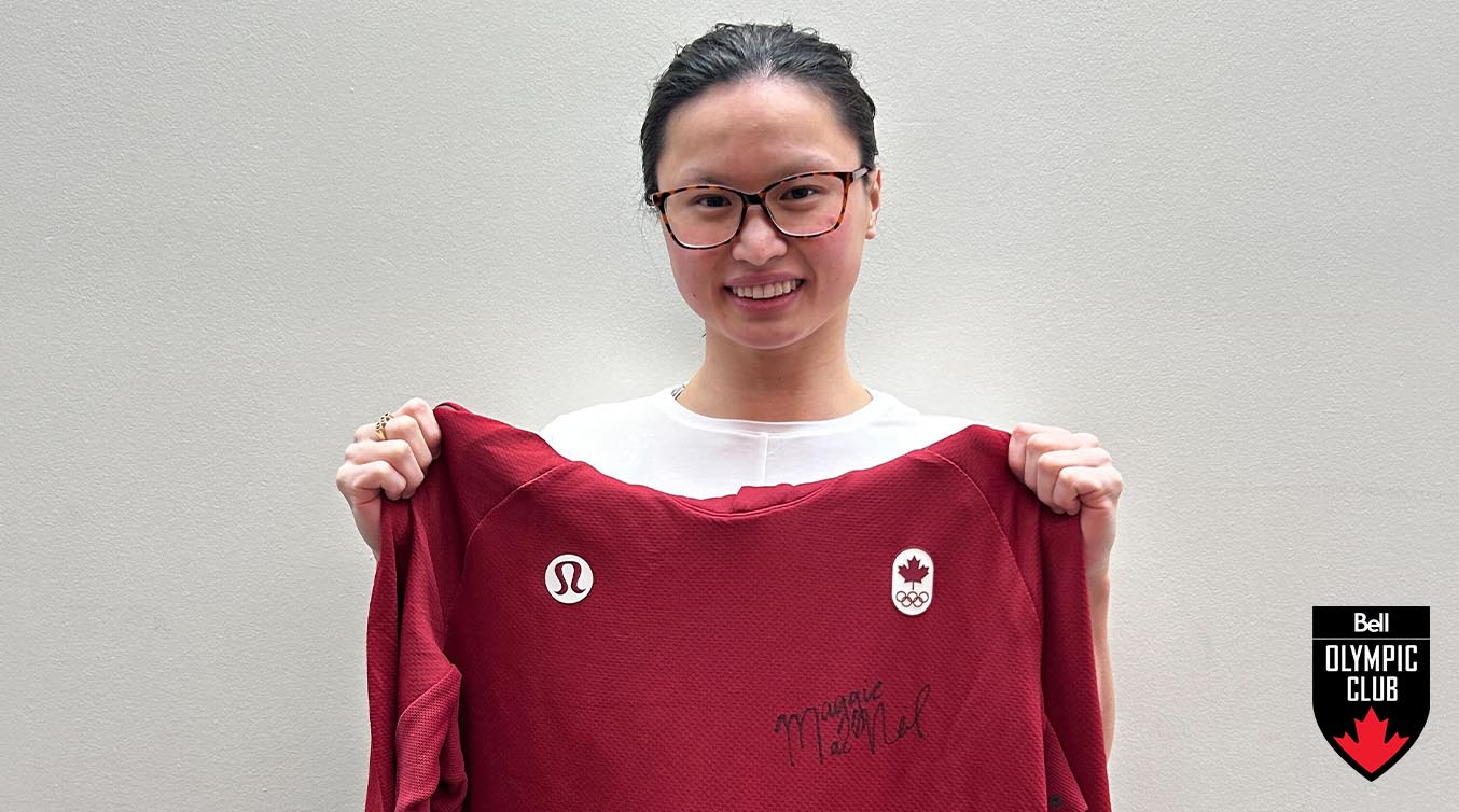 Maggie Mac Neil smiling while holding up a signed sweater