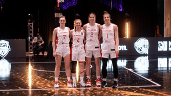 Team Canada's 3x3 women's basketball team stands arm in arm while wearing white and red jerseys