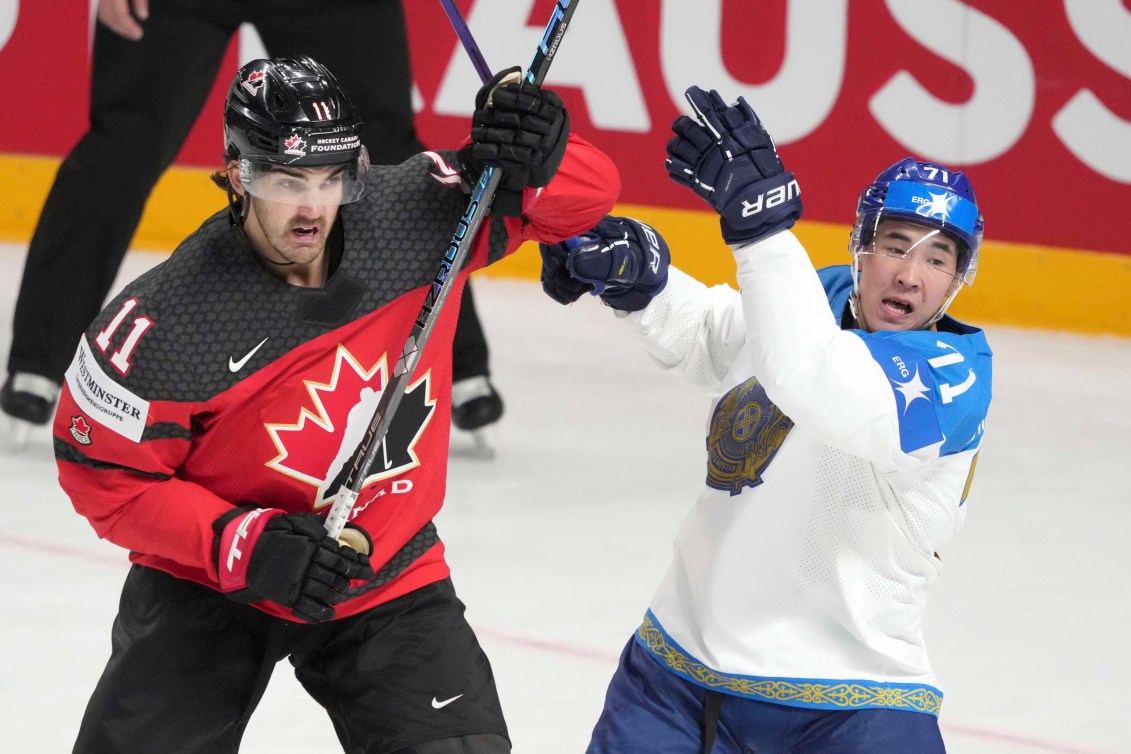 Jack McBain of Canada fights for a puck with Madi Dikhanbek of Kazakhstan during the group B match between Canada and Kazakhstan at the ice hockey world championship in Riga, Latvia, Wednesday, May 17, 2023.