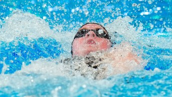 Ingrid Wilm's head breaks the water while she swims backstroke
