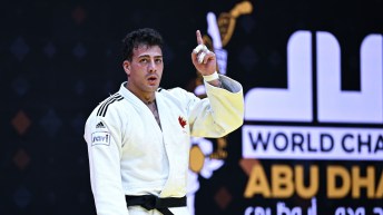 Shady Elnahas in a white judo uniform raises a finger in victory