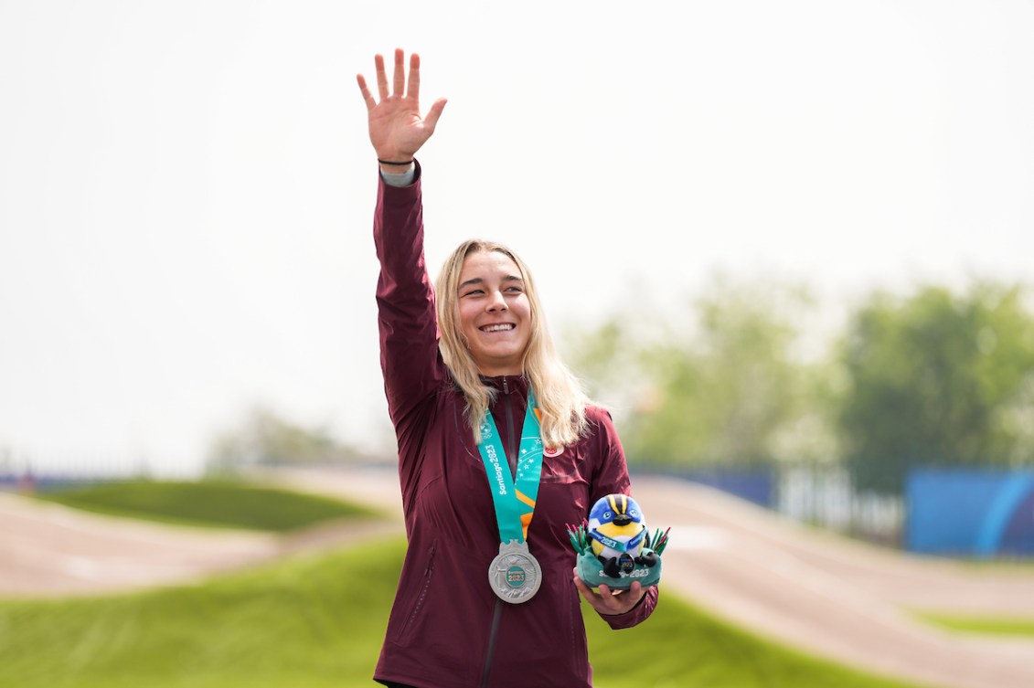 Molly Simpson raises her hand in the air while wearing her silver medal