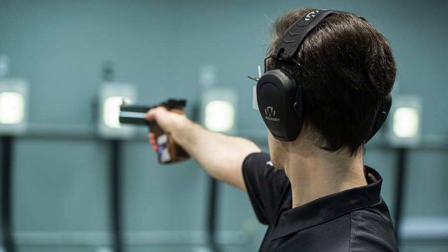 Michele Esercitato competes in the 10m air pistol while wearing large headphones.