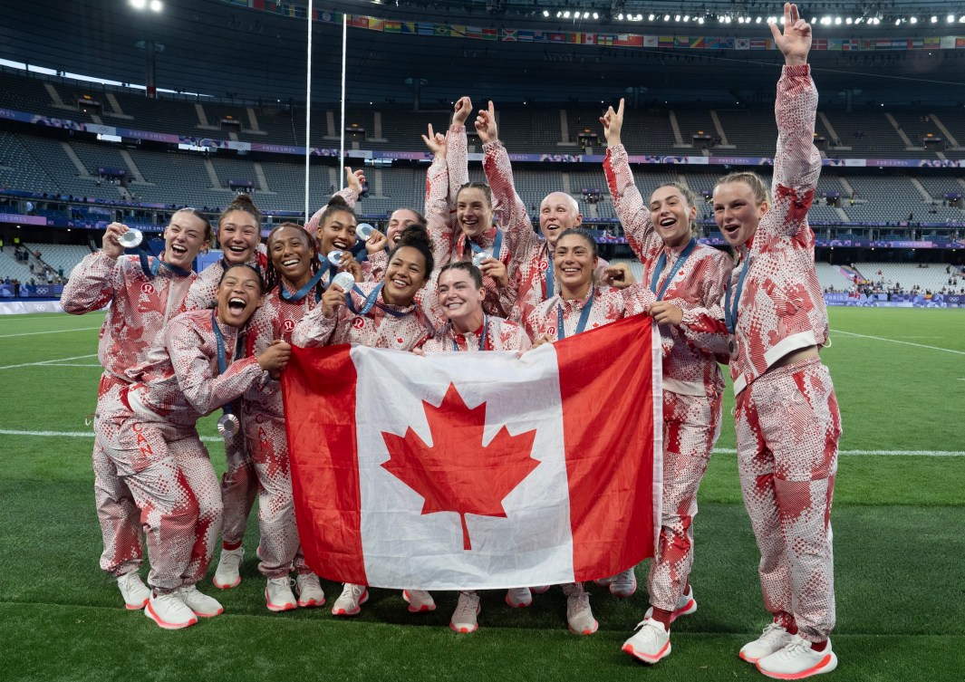 Team Canada celebrates with their silver medals and a Canadian flag.