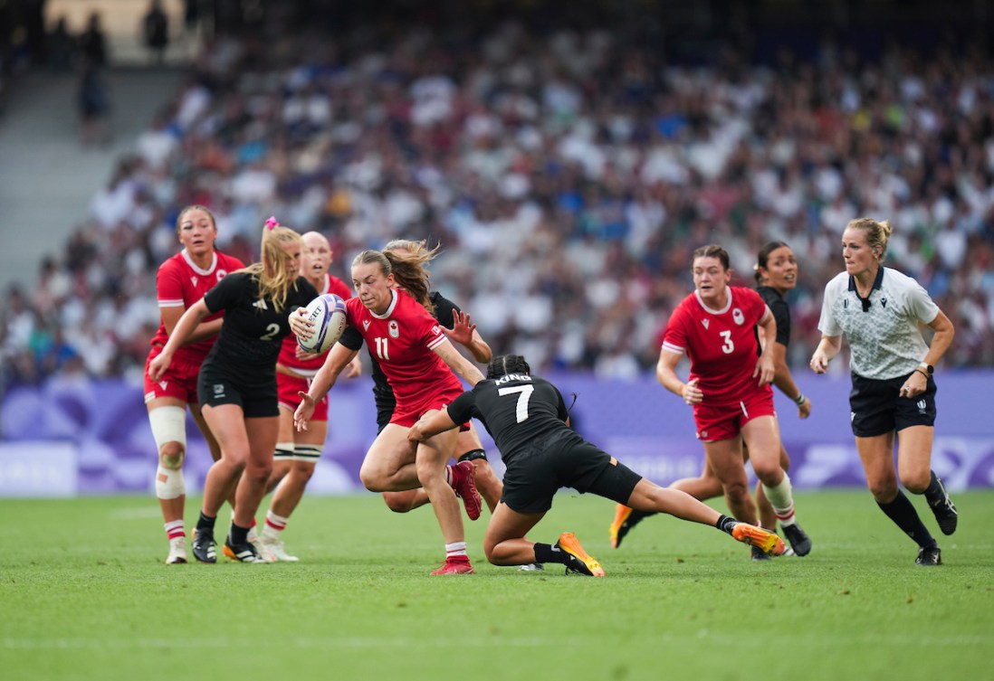 PIper Logan runs with the rugby ball while a New Zealand player tries to pull her down 