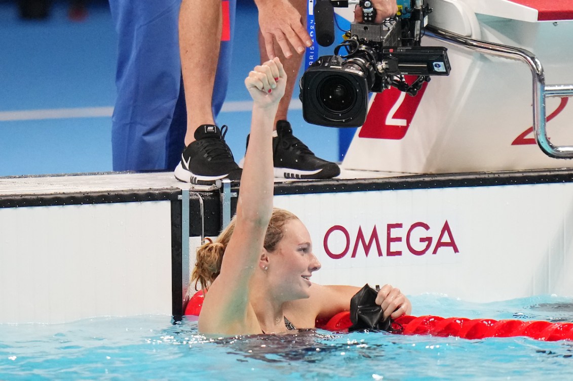 Summer McIntosh raises her fist in celebration while hanging onto the lane rope