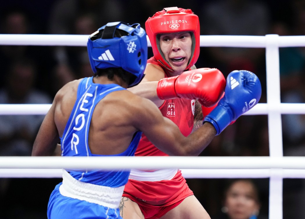 Tammara Thibeault punches an opponent while wearing a red helmet and singlet