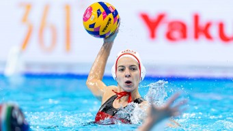 A female water polo player holds the ball above her head ready to throw