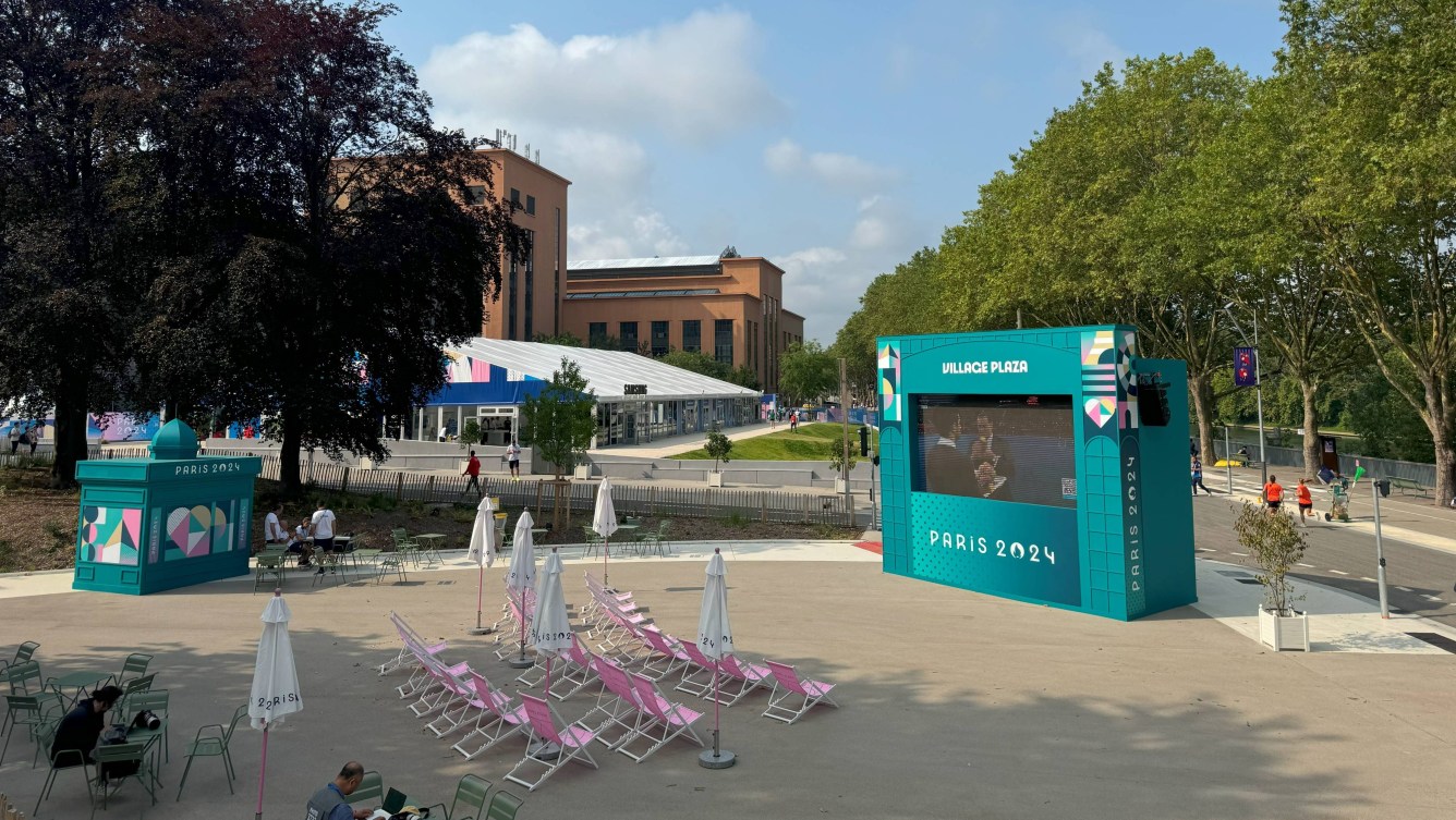 Pink outdoor chairs face towards a teal outdoor television