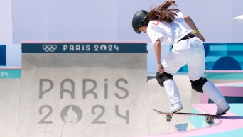 Fay De Fazio Ebert dressed in white balances on her skateboard at the lip of a ramp