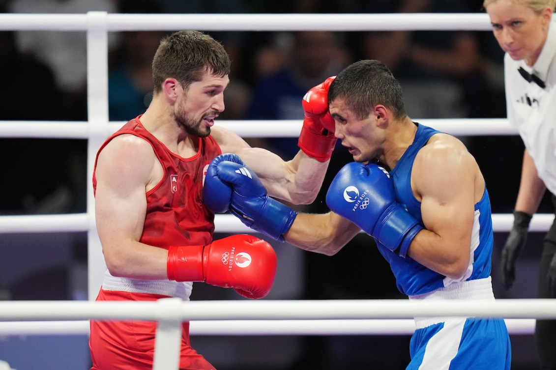 Wyatt Sanford in red boxing singlet and glove punches at a boxer in blue 