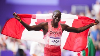 Marco Arop stands with the Canadian flag held over his shoulders