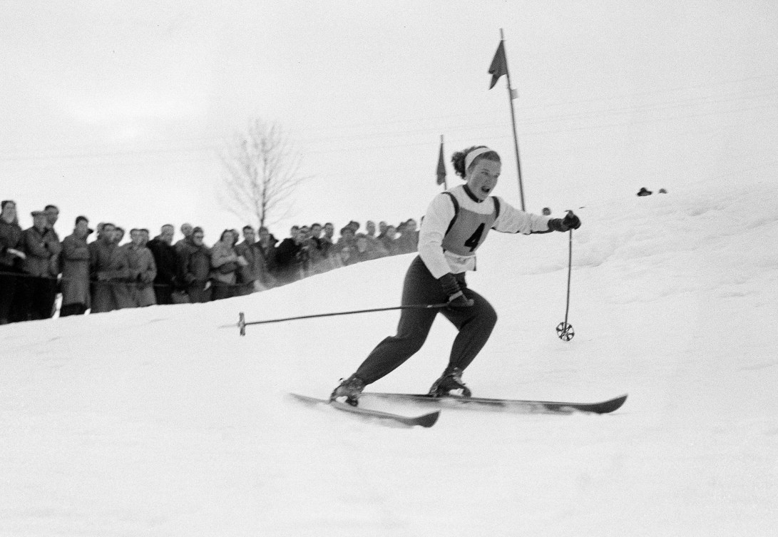 Black and white image of a female skier going down a course