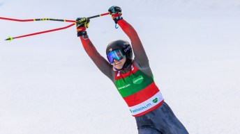 India Sherret holds he ski poles up over her head in celebration