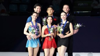 Three figure skating pairs stand on the podium with medals and flowers