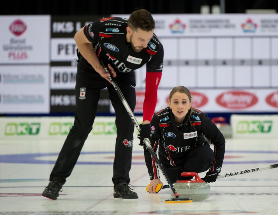 Brett Gallant sweeps a red stone just thrown by Jocelyn Peterman