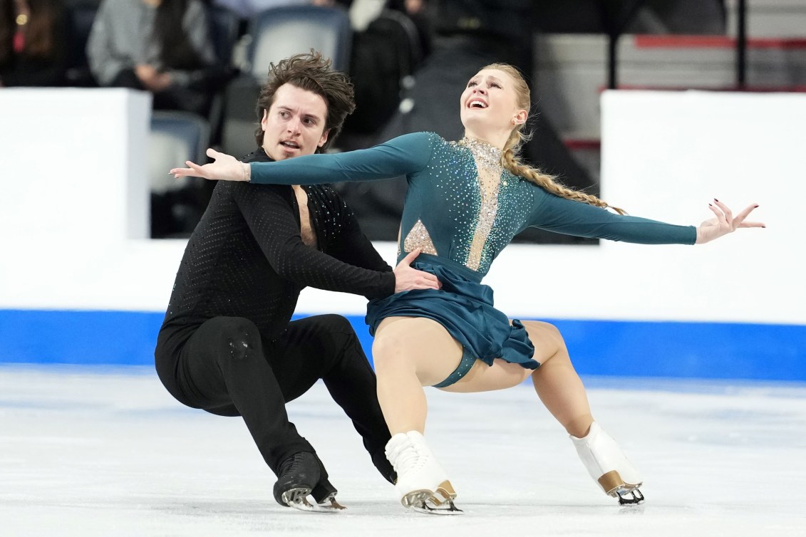 Alicia Fabbri in a green dress performs a squat position with partner Paul Ayer in a black pants and top