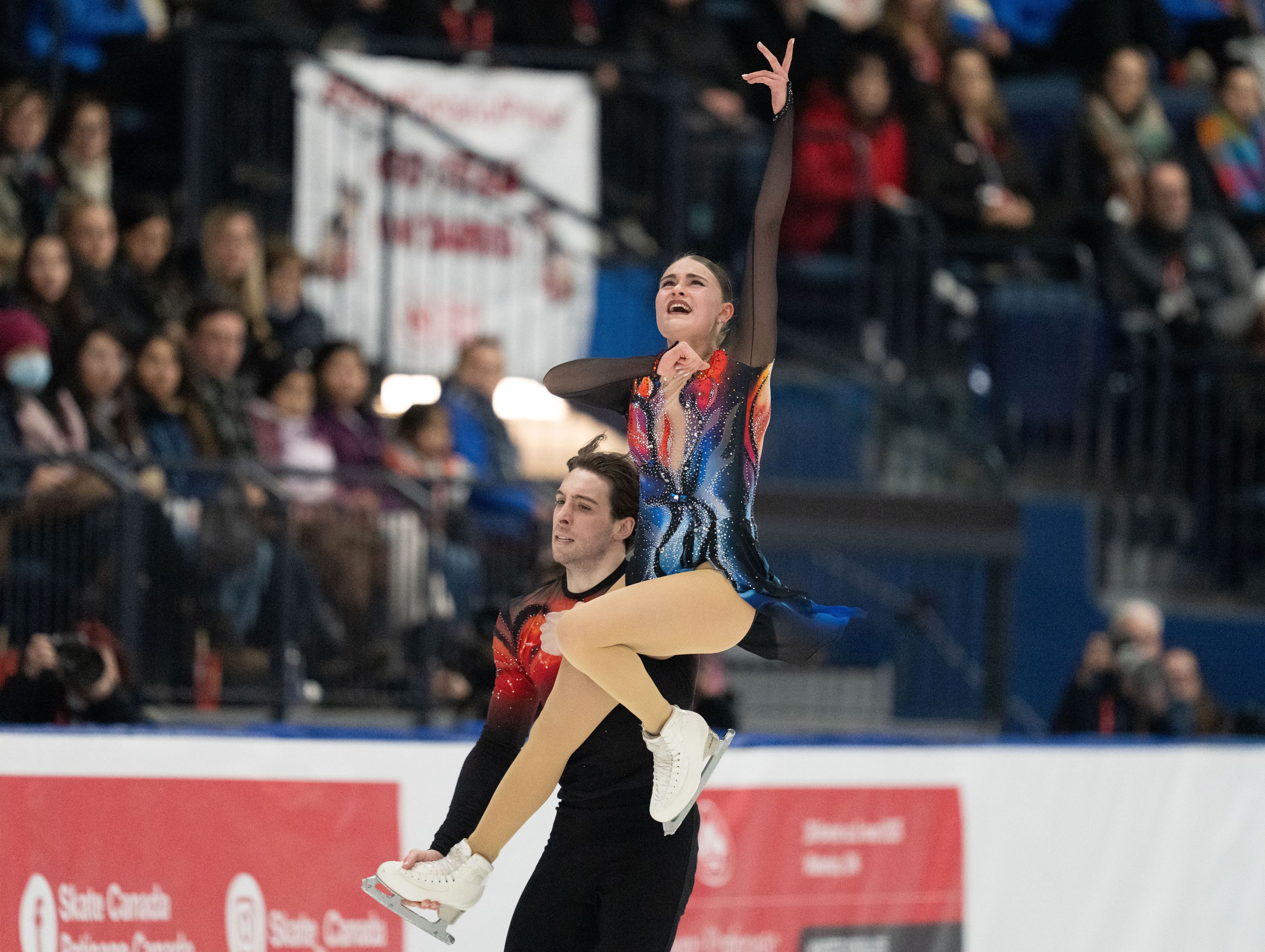 Kelly Ann Laurin in a multi coloured dress is carried by partner Loucas Ethier