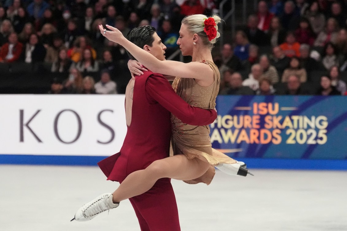 Piper Gilles in a gold dress and Paul Poirier in a red backless suit perform a dance lift