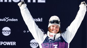 Maia Schwinghammer raises are arms above her head standing on the podium