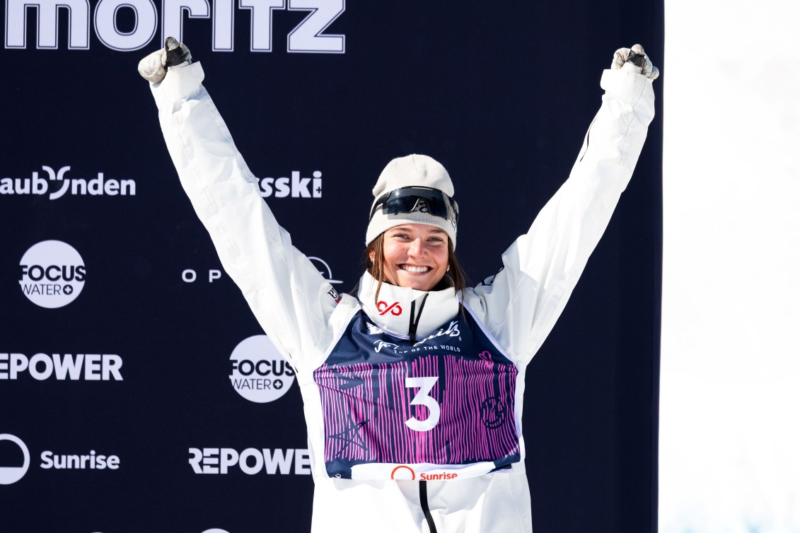 Maia Schwinghammer raises are arms above her head standing on the podium