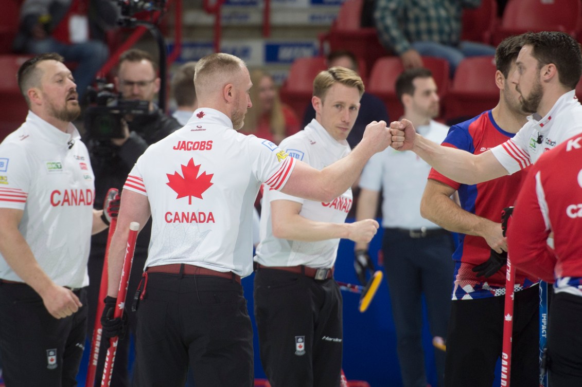 Dressed in white shirts, the four members of Team Canada fist tap each other