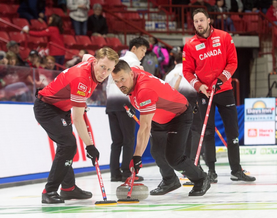 Dressed in red shits, Brett Gallant watches the red stone he threw being swept by Marc Kennedy and Ben Hebert