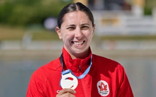 Katie Vincent smiles with gold medal on podium, after winning C1 500m final in Poland.