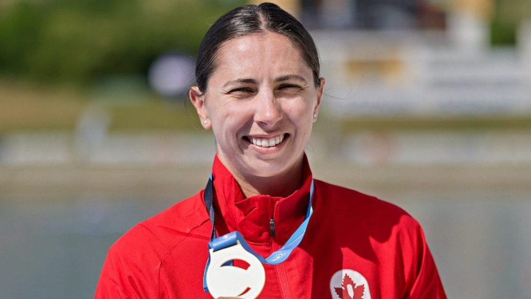Katie Vincent smiles with gold medal on podium, after winning C1 500m final in Poland.