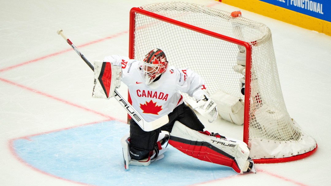 Jordan Binnington makes a save while wearing a white Team Canada jersey