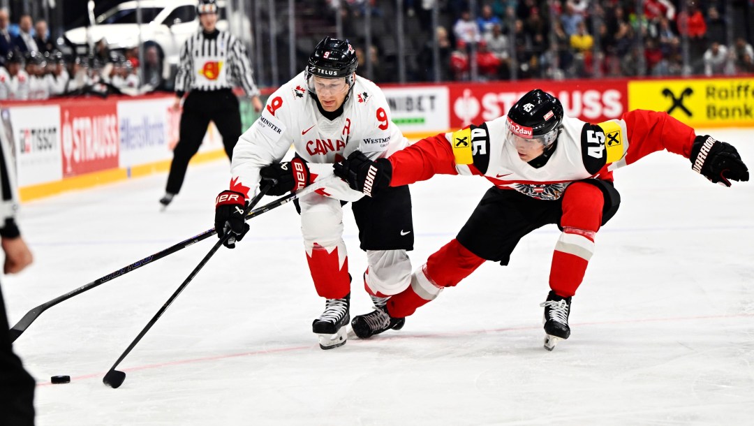 Canada's Nate MacKinnon, left, and Austria's Gregor Biber, right, challenge for the puck during the IIHF Ice Hockey World Championship group A match between Canada and Austria in Stockholm, Sweden, Thursday, May 15, 2025. (Anders Wiklund/TT News Agency via AP)