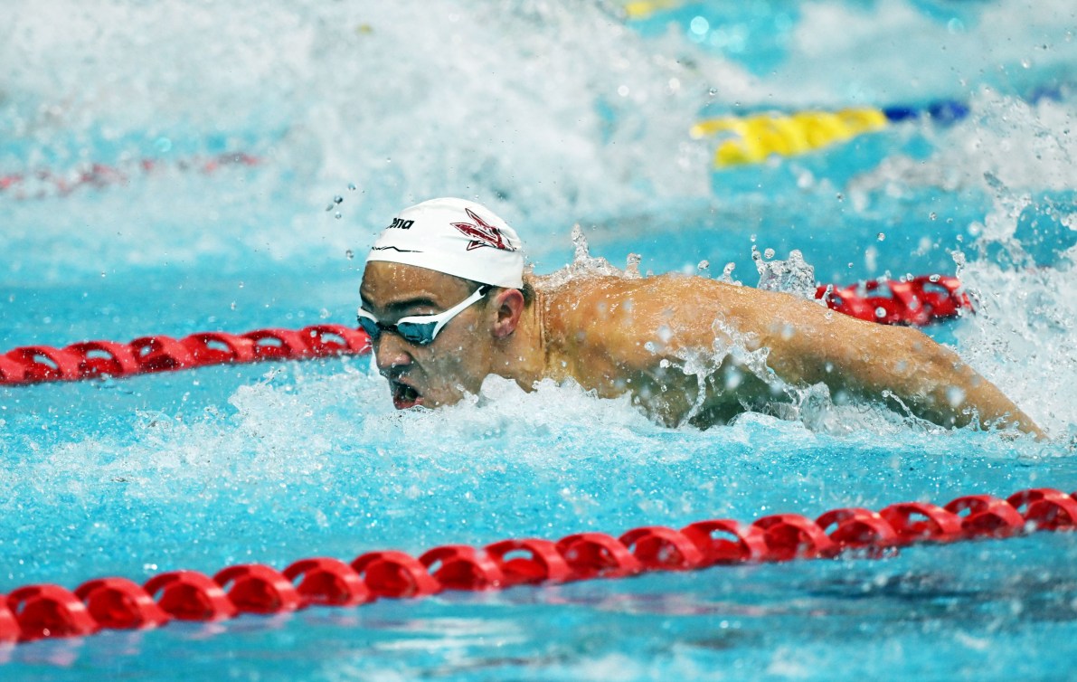 Wearing a white cap Ilya Kharun swims butterfly stroke