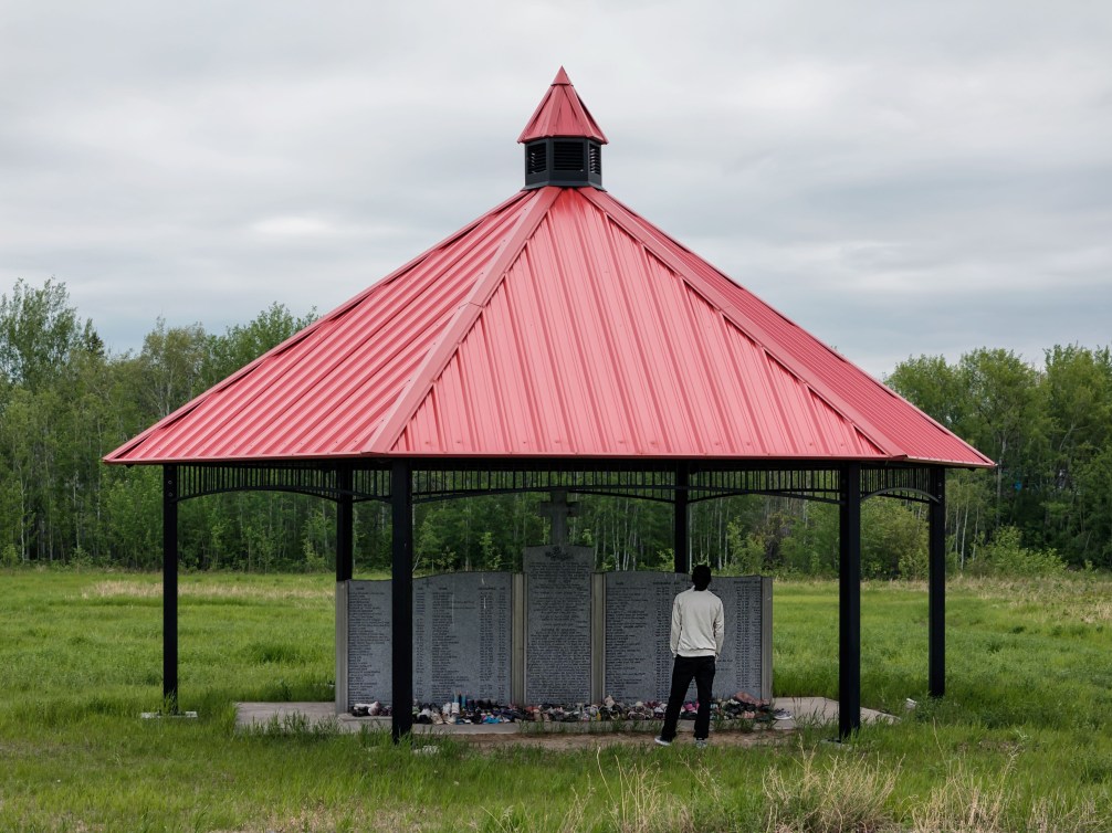 Liam Gill pays his respects in front of a memorial to residential school victims in Fort Providence