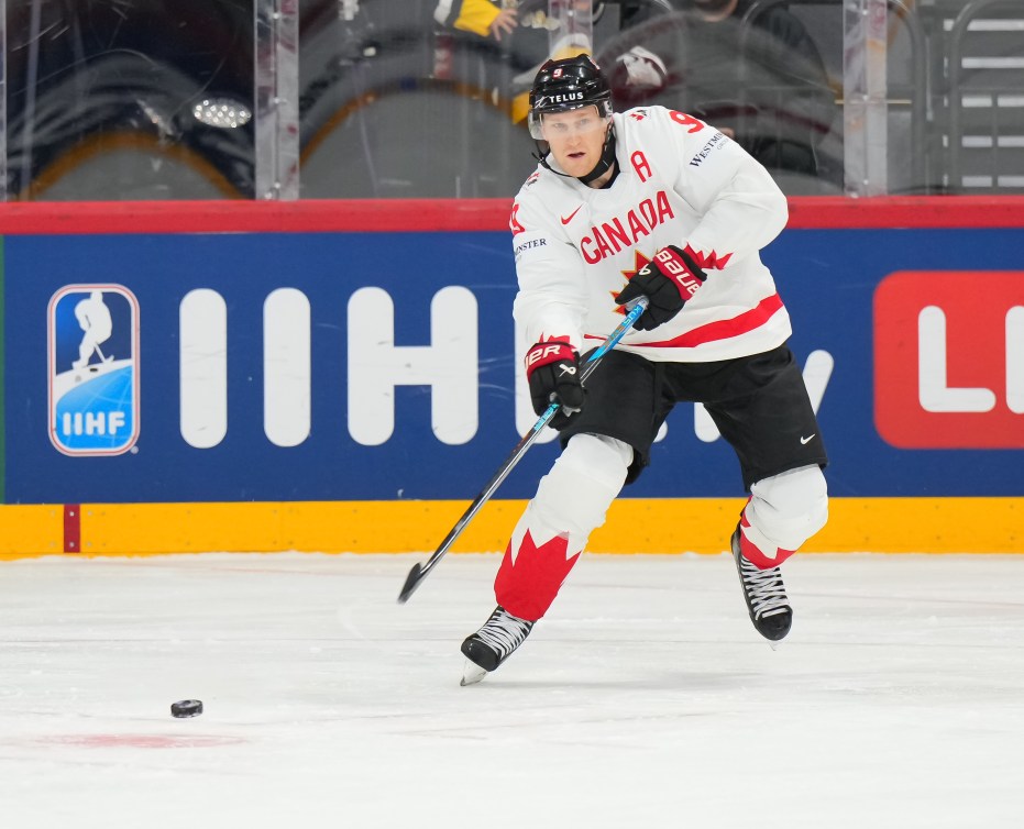 Nathan MacKinnon takes a shot while wearing a white Team Canada jersey